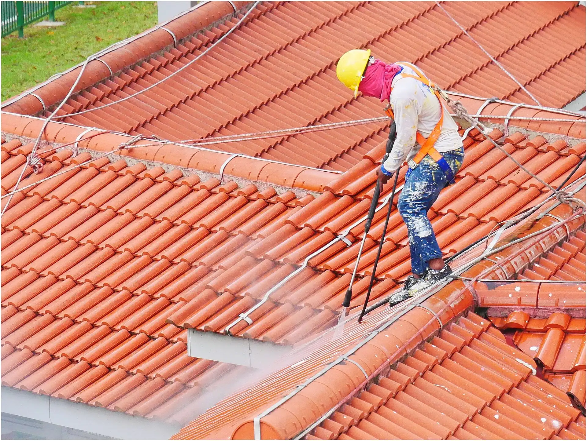 Worker pressure washing a tile roof
